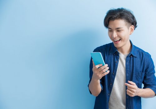 man student use phone man student smile and use phone isolated on blue background,asian