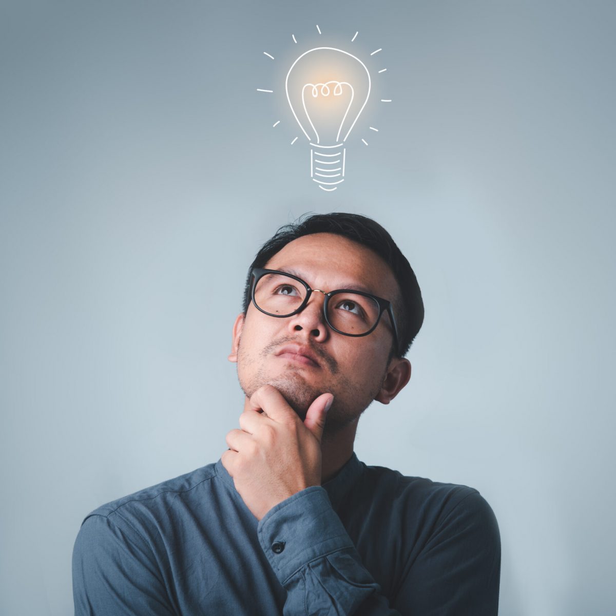 Thinking asian man in glasses looking up with light idea bulb above head on gray background.creative idea.Concept of idea and innovation Thinking asian man in glasses looking up with light idea bulb above head on gray background.creative idea.Concept of idea and innovation